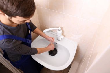 Plumber repairing sink with hand plunger clipart