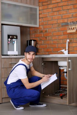Handsome plumber in kitchen clipart