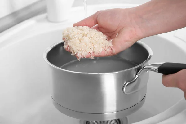 Rinsing rice in saucepan — Stock Photo, Image