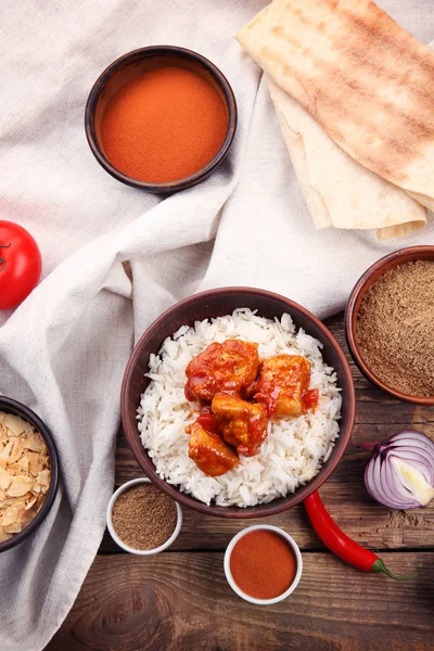 Tigela com delicioso frango tikka masala, arroz e especiarias na mesa de madeira — Fotografia de Stock