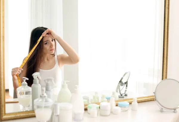 Mujer que mide la longitud del cabello delante del espejo — Foto de Stock