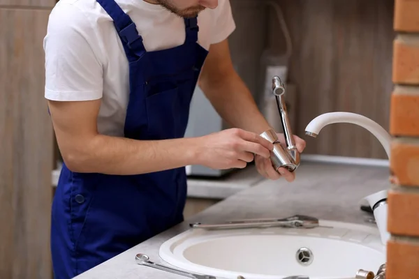 Handsome plumber in kitchen — Stock Photo, Image