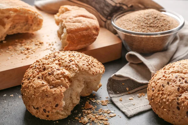 Pães partidos e tigela de vidro de migalhas de pão no fundo cinza — Fotografia de Stock