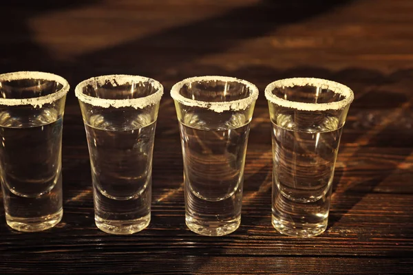 Fila de tiros de tequila em fundo de madeira — Fotografia de Stock