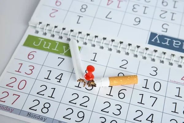 Sigaretta rotta attaccata al calendario, primo piano — Foto Stock