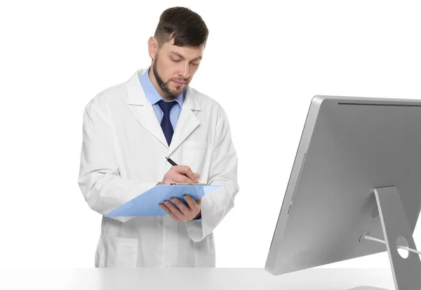 Young pharmacist with clipboard near table on white background — Stock Photo, Image