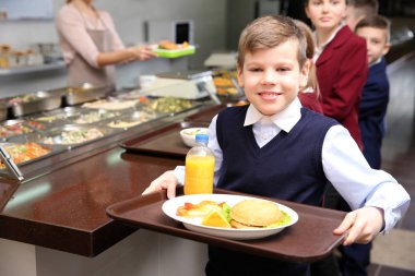 Sevimli kız lezzetli yemek tepsisiyle okul kafeteryasında holding