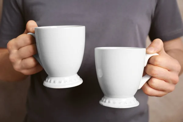 Blank white cups in hands — Stock Photo, Image