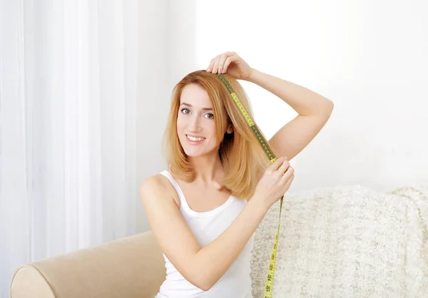 Mulher Bonita Medindo Comprimento Cabelo Enquanto Sentada Sofá Casa — Fotografia de Stock