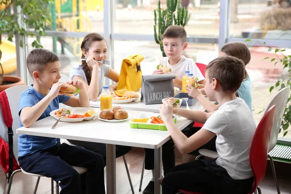 Copiii stau la masa de cantină în timp ce mănâncă prânzul — Fotografie, imagine de stoc