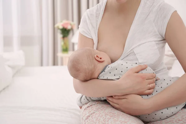 Mladá žena kojení její malé dítě doma — Stock fotografie