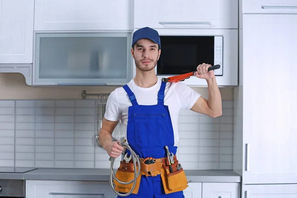 Knappe jonge loodgieter in keuken — Stockfoto