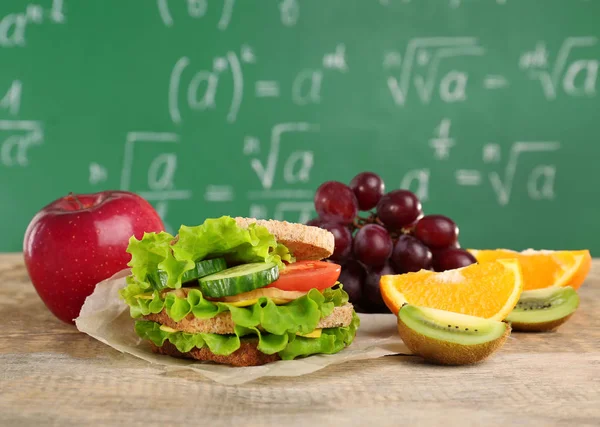 Deliciosos alimentos e frutas na mesa de madeira contra o fundo do quadro — Fotografia de Stock