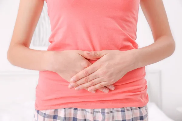 Giovane donna con le mani sulla pancia a casa, primo piano — Foto Stock