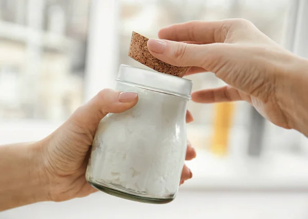 Hand holding jar with coconut oil — Stock Photo, Image