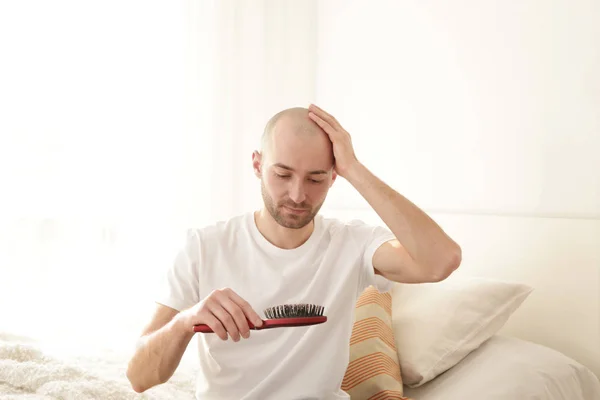 Koncept ztráty vlasů. Mladý muž s hřebenem doma — Stock fotografie