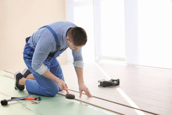 Trabalhador que instala piso laminado — Fotografia de Stock
