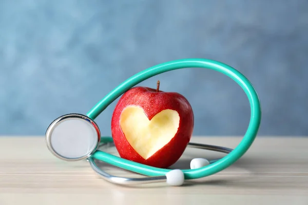 Яблоко с разрезом в форме сердца и стетоскопом — стоковое фото
