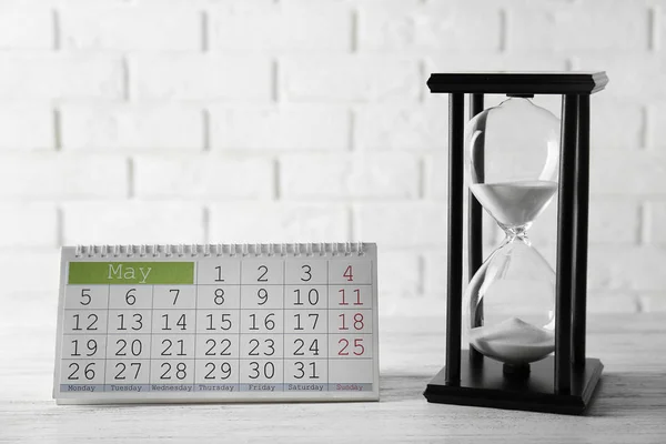 Hourglass with white sand and calendar — Stock Photo, Image