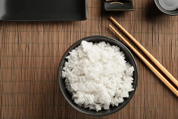 Cuenco de arroz y palillos en estera de bambú — Foto de Stock