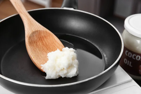 Spoon with coconut oil in frying pan — Stock Photo, Image