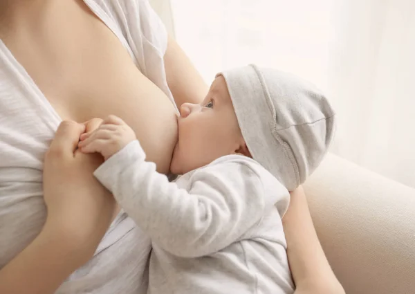 Молодая женщина кормит грудью своего малыша дома, крупным планом — стоковое фото