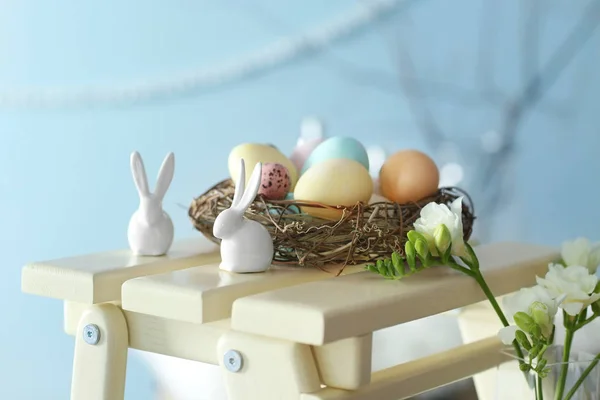 Králíci a hnízdo s malovanými vejci na dekorativní dřevěná stolička — Stock fotografie