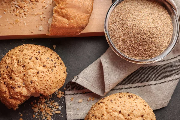 Glass bowl of bread crumbs and broken loafs on grey background — Stock Photo, Image