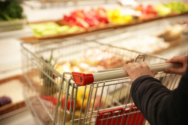 Manos femeninas sosteniendo carro de supermercado —  Fotos de Stock