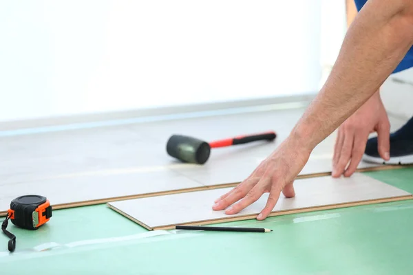 Mãos de trabalhador masculino instalando piso laminado — Fotografia de Stock