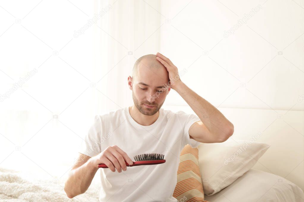 Hair loss concept. Young man with comb at home