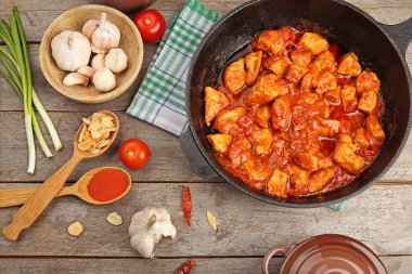 Frying pan with delicious chicken tikka masala on wooden table clipart