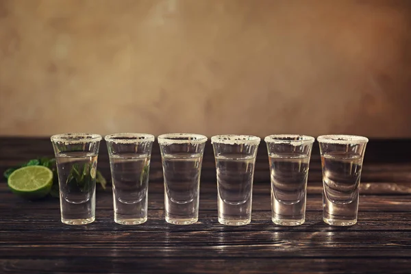 Fila di colpi di tequila sul tavolo di legno — Foto Stock