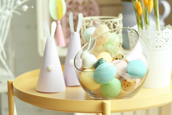 Vase en verre avec œufs de Pâques peints et lapins en papier faits à la main sur la table — Photo