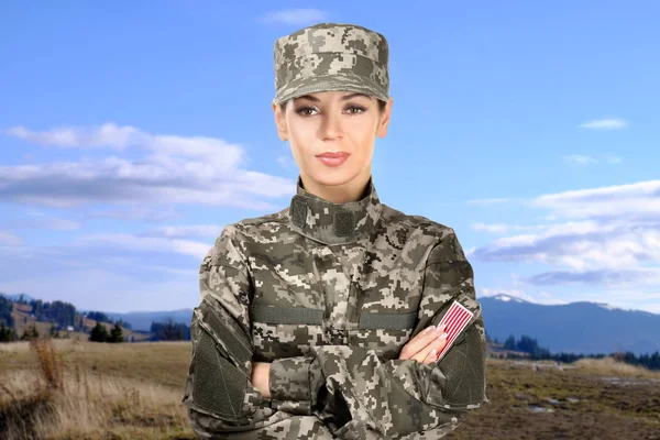 Female soldier in camouflage on landscape background