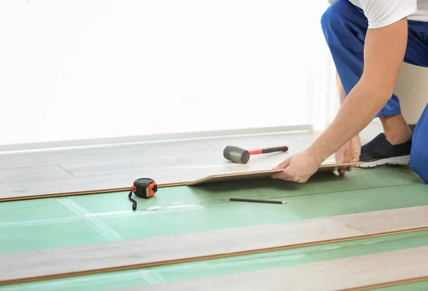 Mãos de trabalhador masculino instalando piso laminado — Fotografia de Stock