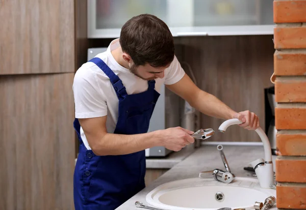 Handsome plumber in kitchen — Stock Photo, Image