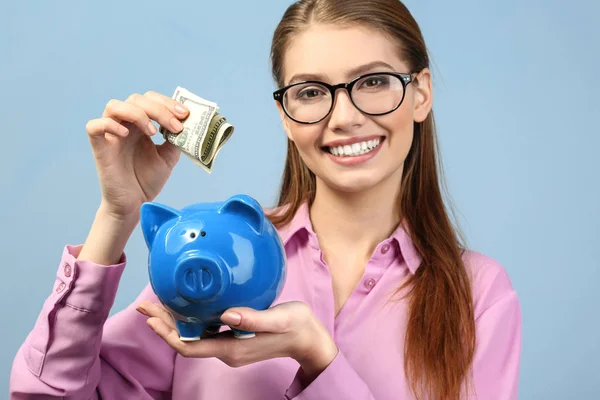 Woman putting money into piggy bank — Stock Photo, Image