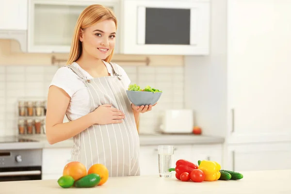 Gravid kvinna anläggning skål med sallad — Stockfoto