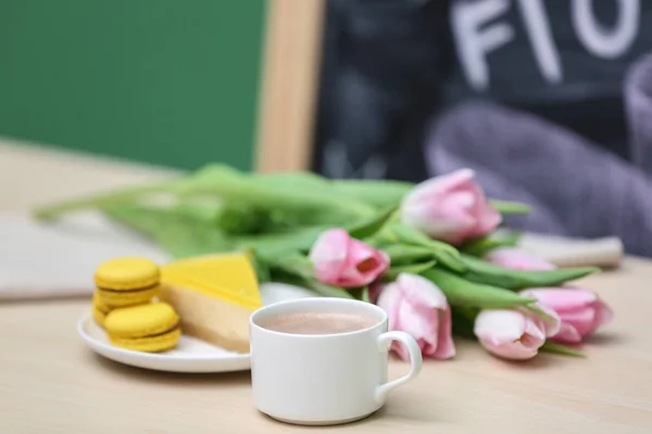 Cup of coffee with cake and bouquet of flowers