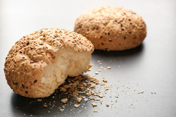 Broken buns with sesame seeds on grey background — Stock Photo, Image