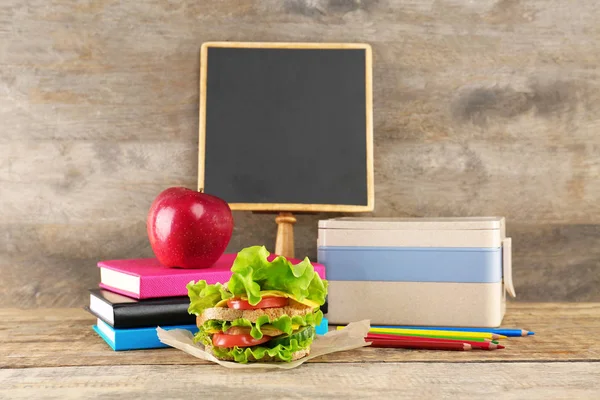 Delicious food, lunch box and school accessories on wooden background — Stock Photo, Image