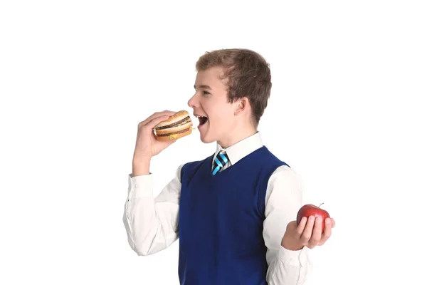 Niedlicher Schuljunge mit Apfel und Hamburger auf weißem Hintergrund — Stockfoto
