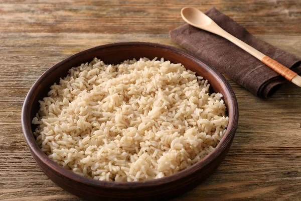 Plaat met bruine rijst op houten tafel achtergrond — Stockfoto
