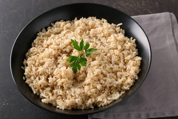 Plaat met bruine rijst op grijze tabelachtergrond — Stockfoto
