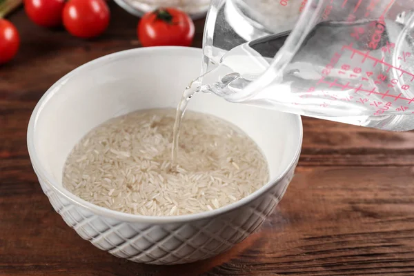 Wasser in Schüssel mit Reis gießen — Stockfoto
