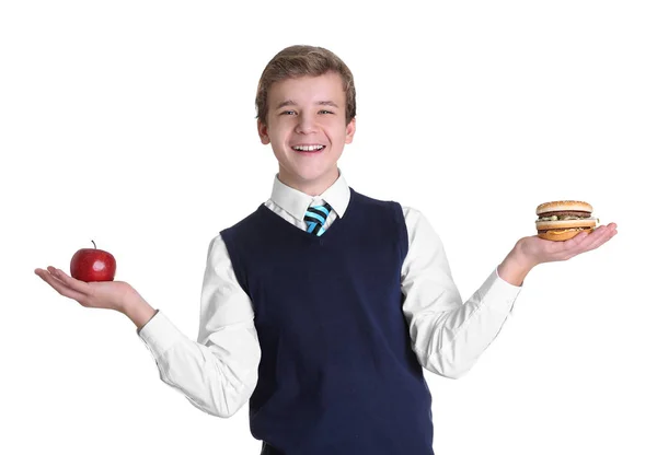 Söt skolpojke med äpple och hamburgare på vit bakgrund — Stockfoto