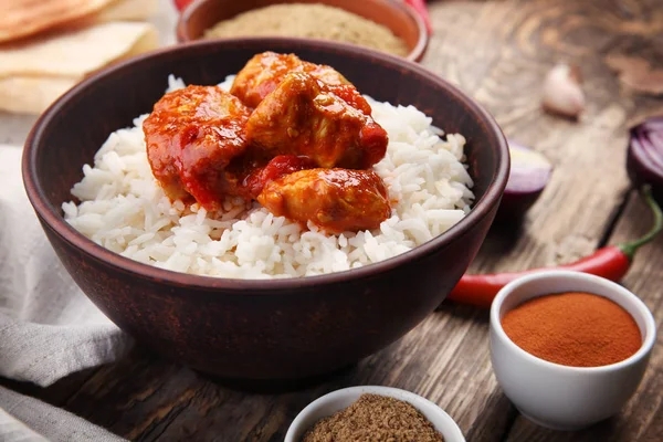 Tigela com delicioso frango tikka masala, arroz e especiarias na mesa — Fotografia de Stock