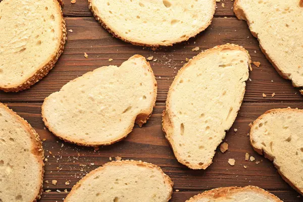 Ломтики и крошки пшеничного хлеба на деревянном фоне — стоковое фото