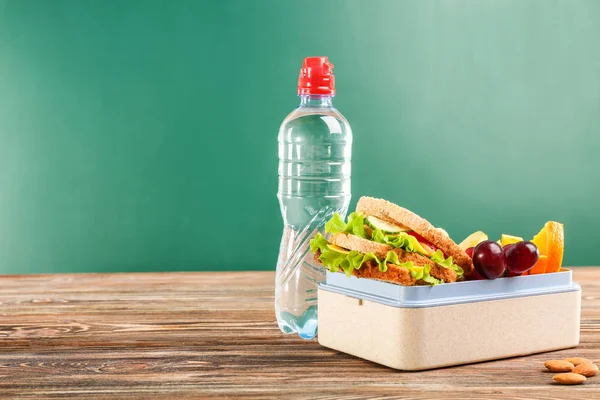 Chutné jídlo v oběd box a láhev vody na dřevěný stůl tabuli pozadí — Stock fotografie